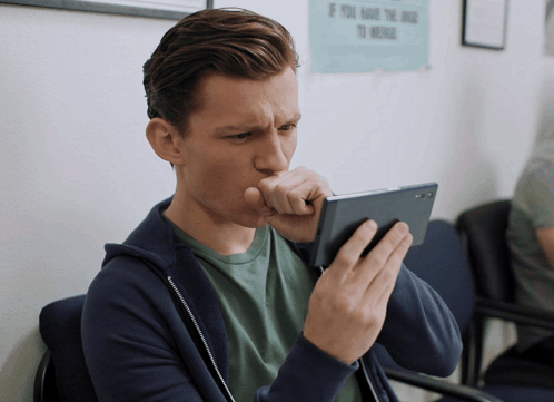 A Man Coughing While Looking At His Cell Phone In Front Of A Sign That Says If You Have The Drug To Medicate GIF