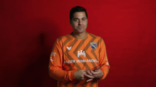 A Man Covering His Face While Holding A Card That Says Kaiser Permanent GIF