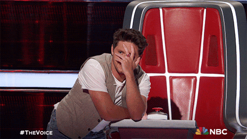 A Man Covering His Face While Sitting In A Chair With The Nbc Logo On The Bottom Right GIF
