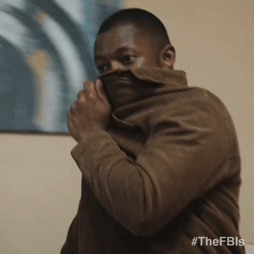 A Man Covering His Face With A Brown Jacket With The Hashtag #Thefbis GIF