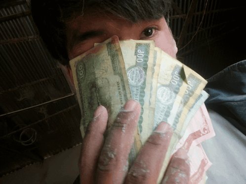 A Man Covering His Face With A Bunch Of Money That Says ' 00P ' On It GIF