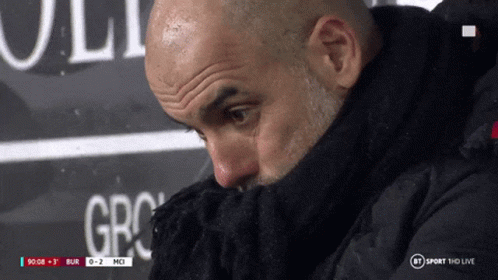 a man covering his face with a scarf in front of a bt sport hd live sign