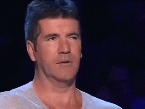 A Man Covering His Face With His Hand In Front Of A Dark Background GIF