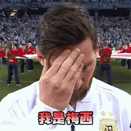 A Man Covering His Face With His Hands In Front Of A Crowd Of People . GIF