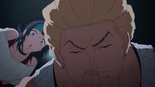 A Man Covering His Mouth With His Finger While A Woman Looks On Behind Him GIF