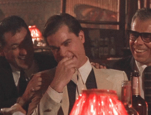 A Man Covering His Mouth With His Hand While Sitting At A Table GIF