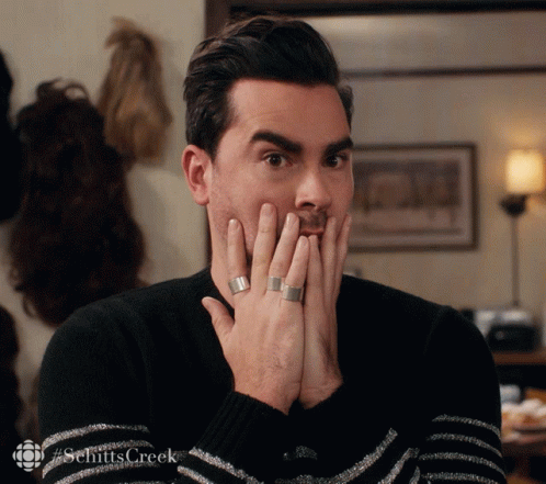 A Man Covering His Mouth With His Hands With A #Schittscreek Logo In The Corner GIF