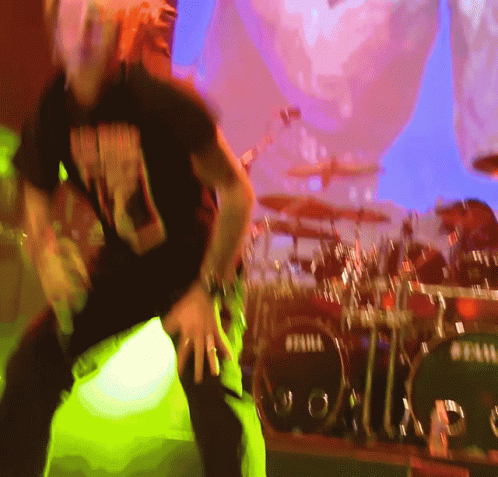 A Man Dancing In Front Of A Drum Set That Says Tama GIF