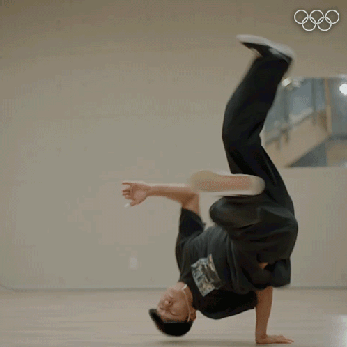 A Man Doing A Handstand In Front Of A Mirror With The Olympic Rings In The Background GIF