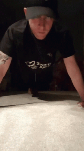 A Man Doing Push Ups With A Swans Aid Shirt On GIF