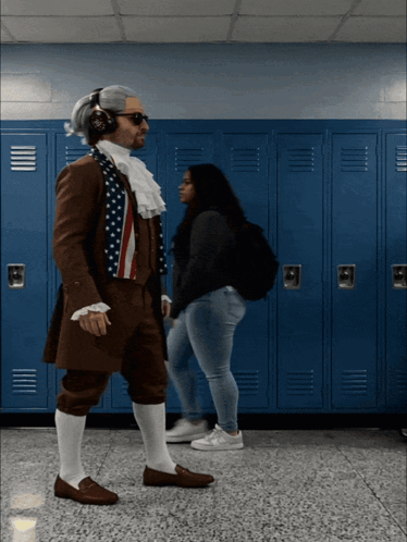 A Man Dressed As Benjamin Franklin Is Walking In A Hallway With Blue Lockers GIF