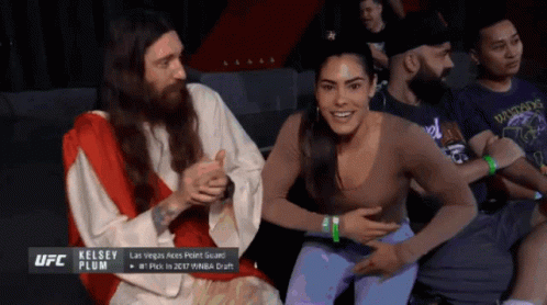 A Man Dressed As Jesus Is Sitting Next To A Woman Who Is Smiling GIF