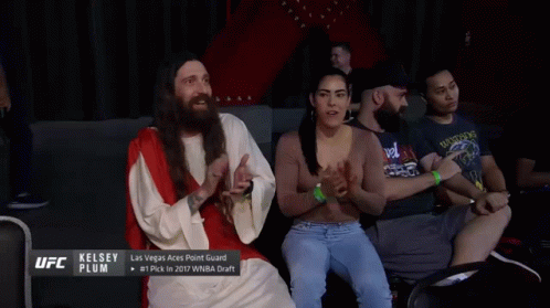 A Man Dressed As Jesus Talks To A Woman In A Crowd GIF