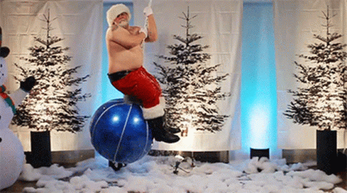A Man Dressed As Santa Claus Is Riding A Blue Ball GIF