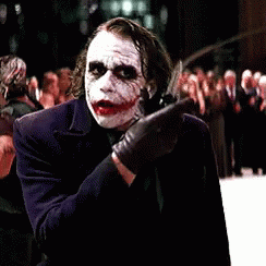 A Man Dressed As The Joker Is Standing In Front Of A Crowd Of People GIF