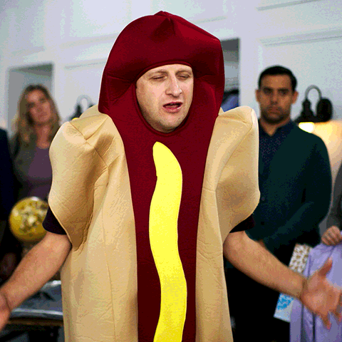 A Man Dressed In A Hot Dog Costume With A Yellow Sausage GIF