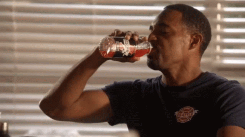 A Man Drinking From A Bottle That Says Firefighter GIF