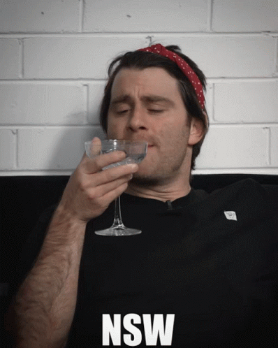 A Man Drinking From A Glass With The Word Nsw On The Bottom Right GIF