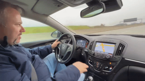A Man Driving A Car With A Map On The Dashboard GIF