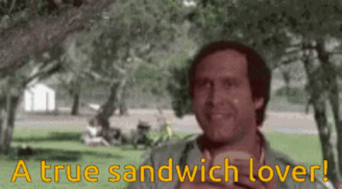A Man Eating A Sandwich In A Park With The Words " A True Sandwich Lover " Written Below Him GIF