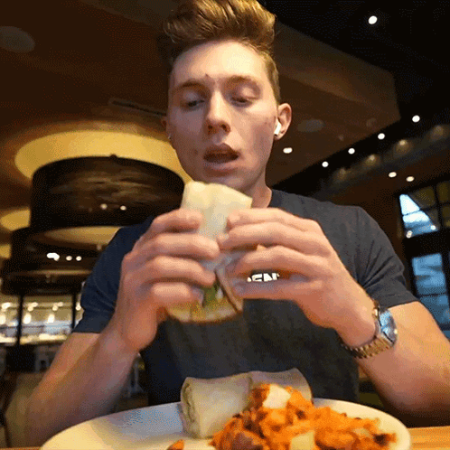 A Man Eating A Sandwich With A Shirt That Says Abercrombie GIF