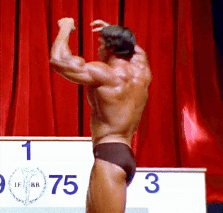 Man Flexing Muscles In Front Of Podium GIF