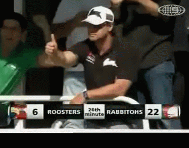 A Man Gives A Thumbs Up In Front Of A Scoreboard That Says Roosters 26Th Minute Rabbitohs 22 GIF