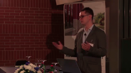 A Man Giving A Presentation In Front Of A Sign That Says ' Bs ' GIF