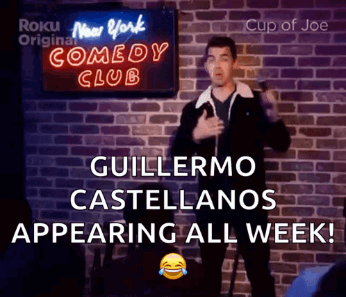 A Man Giving A Speech In Front Of A Sign That Says New York Comedy Club GIF
