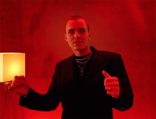 A Man Giving A Thumbs Up In Front Of A Lamp GIF