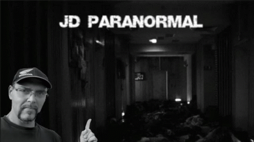 A Man Giving A Thumbs Up In Front Of A Sign That Says Paranormal GIF