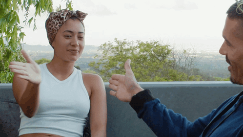 A Man Giving A Woman A Thumbs Up In Front Of Trees GIF