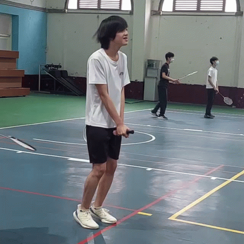 A Man Holding A Badminton Racquet On A Court GIF