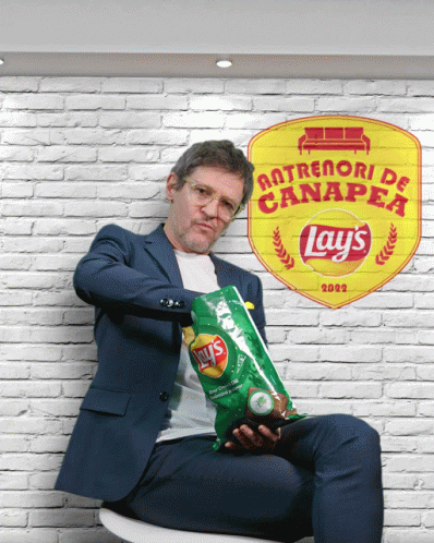 A Man Holding A Bag Of Lays Chips In Front Of A Brick Wall GIF
