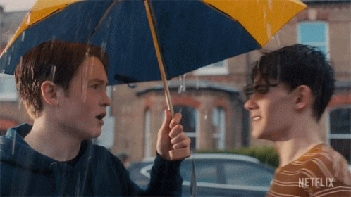 A Man Holding A Blue And Yellow Umbrella With Netflix Written On The Bottom GIF