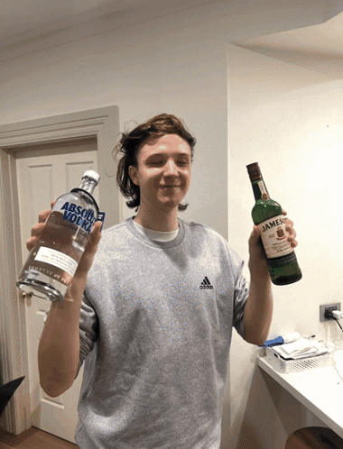 a man holding a bottle of absolut vodka next to a bottle of jameson
