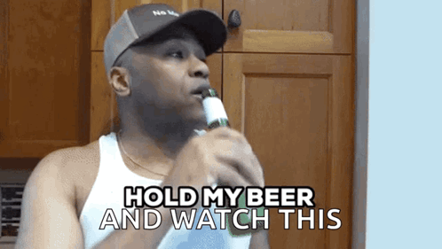 A Man Holding A Bottle Of Beer With The Words Hold My Beer And Watch This Below Him GIF