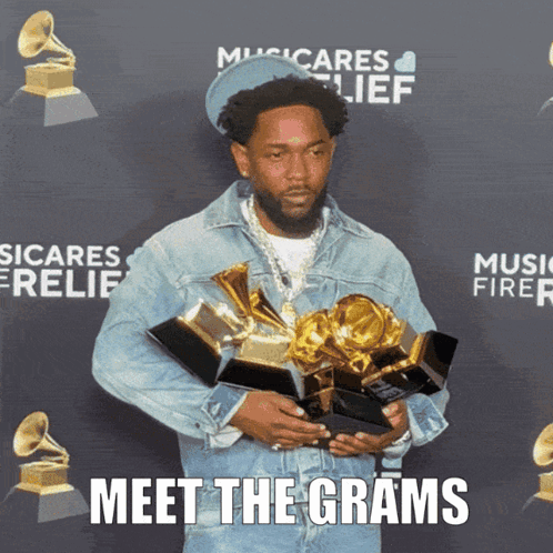 A Man Holding A Bunch Of Awards With The Words Meet The Grams Written Below Him GIF