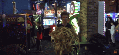 A Man Holding A Bunch Of Spaghetti In Front Of A Machine That Says Ticket Eater GIF