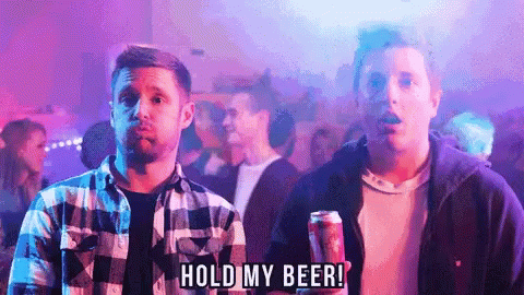 A Man Holding A Can Of Beer With The Words Hold My Beer Below Him GIF