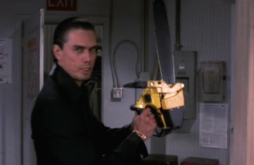 A Man Holding A Chainsaw In Front Of A Sign That Says Exit GIF