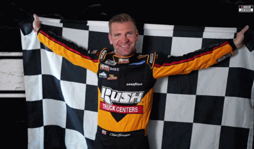 A Man Holding A Checkered Flag That Says Rush Truck Centers On It GIF