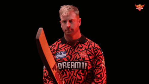 A Man Holding A Cricket Bat With The Word Realm On His Jersey GIF