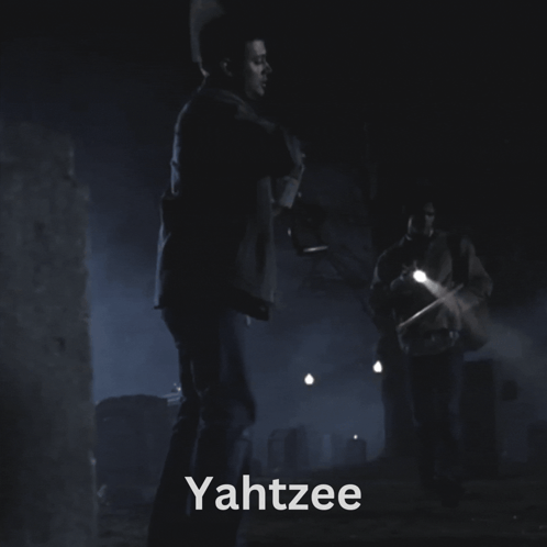 A Man Holding A Flashlight In A Dark Room With The Word Yahtzee On The Bottom GIF
