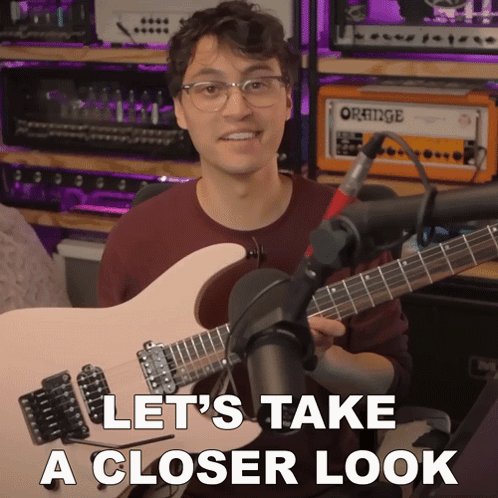 A Man Holding A Guitar In Front Of An Orange Amplifier GIF