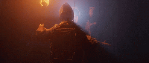 A Man Holding A Gun In A Dark Room With A Light Behind Him GIF
