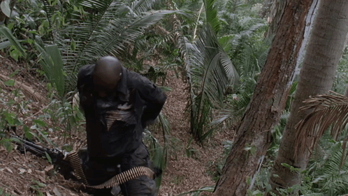 A Man Holding A Gun In A Jungle With The Words I 'M Gonna Have Me Some Fun Below Him GIF
