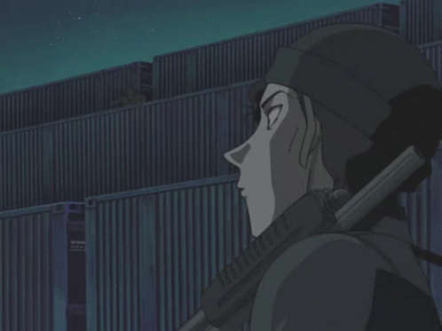 a man holding a gun in front of a building at night