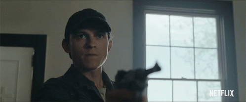 A Man Holding A Gun In Front Of A Window With Netflix Written On The Bottom Right GIF