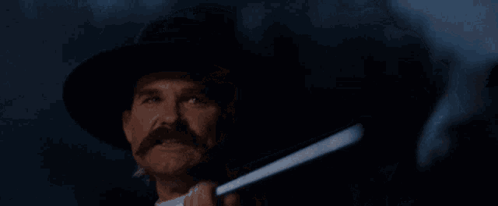 A Man Holding A Gun With The Words " Hell 'S Coming With Me " Behind Him GIF